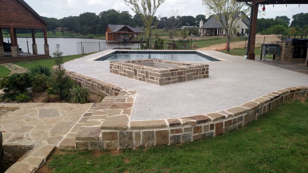stamped concrete deck with fire pit by pool